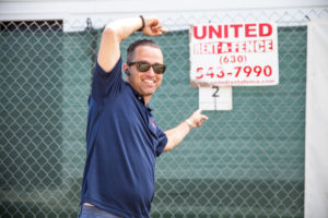 Louie Pointing at a United Rent-A-Fence Sign